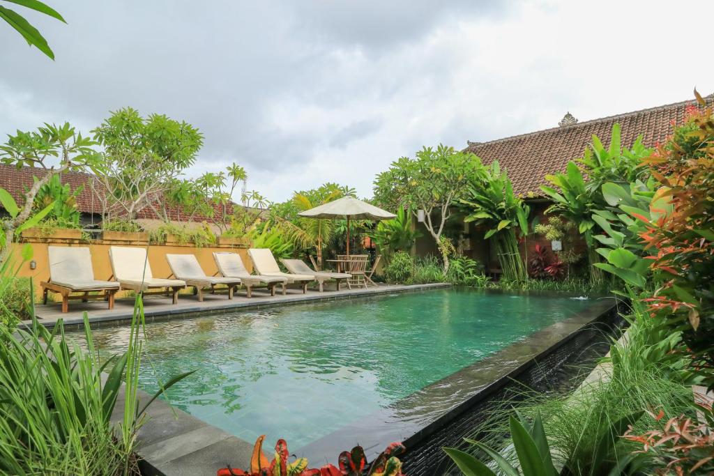 a swimming pool in a garden with lounge chairs at Bali Sunshine Ubud in Ubud