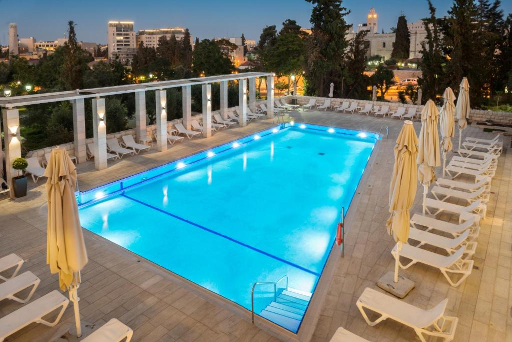 ein großer Pool mit Stühlen und Sonnenschirmen in der Unterkunft Leonardo Plaza Hotel Jerusalem in Jerusalem