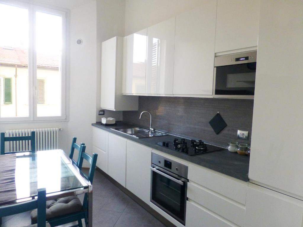 een keuken met witte kasten, een tafel en een wastafel bij Casa "Le Cascine", comfortable apartment... in Florence
