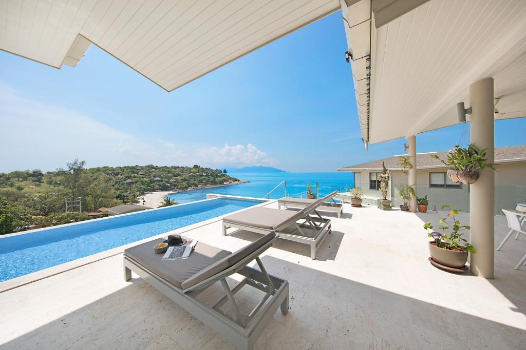 un patio con mesas y vistas al océano en Samui Bayside Luxury Villas en Choeng Mon Beach