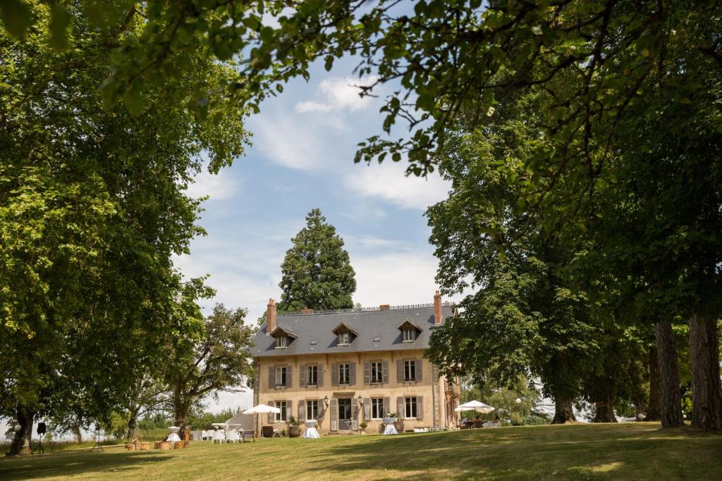 une grande maison avec un arbre en face dans l'établissement Domaine de Savigny, à Saint-Saulge