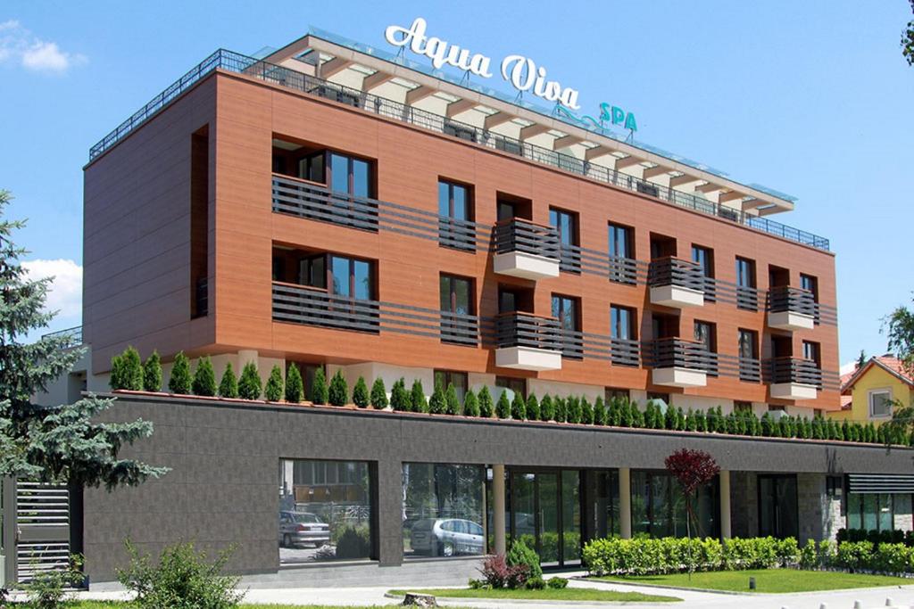 ein großes orangefarbenes Gebäude mit Balkonen darauf in der Unterkunft Aqua Viva Spa Hotel in Welingrad