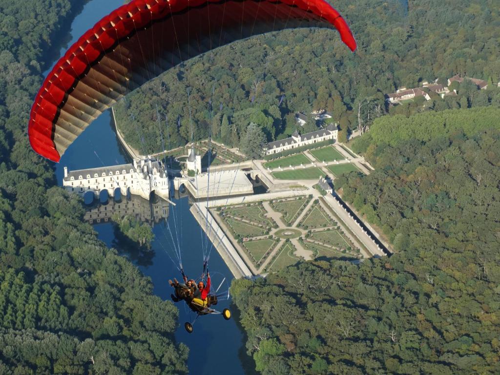 un parapente survolant l'eau avec un château dans l'établissement gîte papillon 4, à Civray-de-Touraine