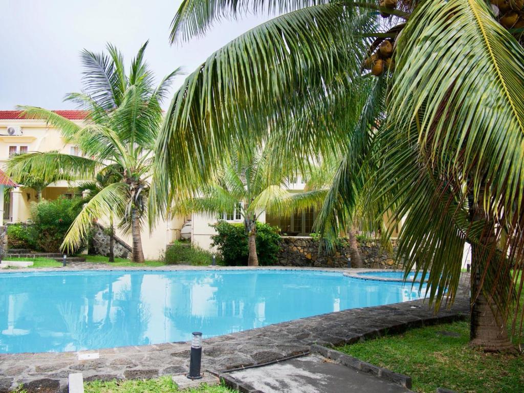 a large blue swimming pool with palm trees next to a building at Azure Villa in Belle Mare