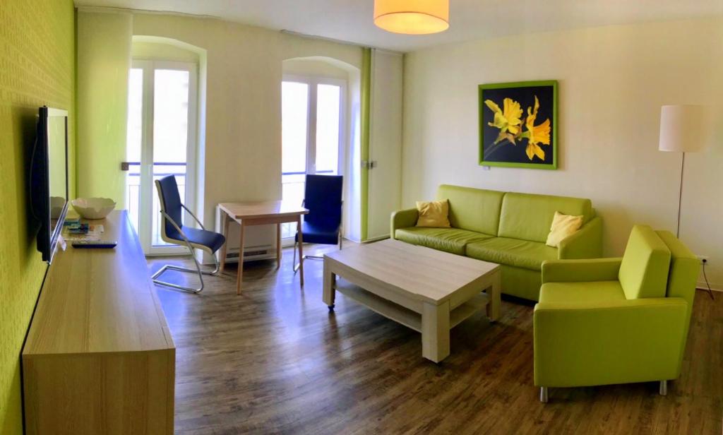 uma sala de estar com um sofá verde e uma mesa em Ferienwohnung am Pfaffe-Kai em Brandemburgo no Havel