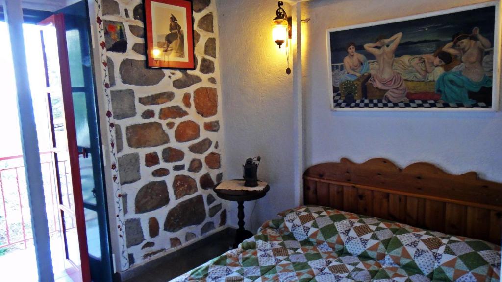 a bedroom with a bed and a stone wall at Tramontana in Hydra