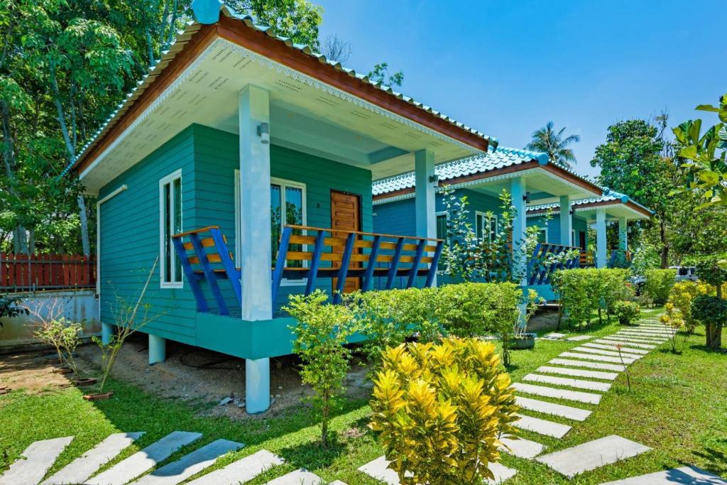 a small blue house with chairs in the yard at RAT VILLA in Ban Pa Khlok