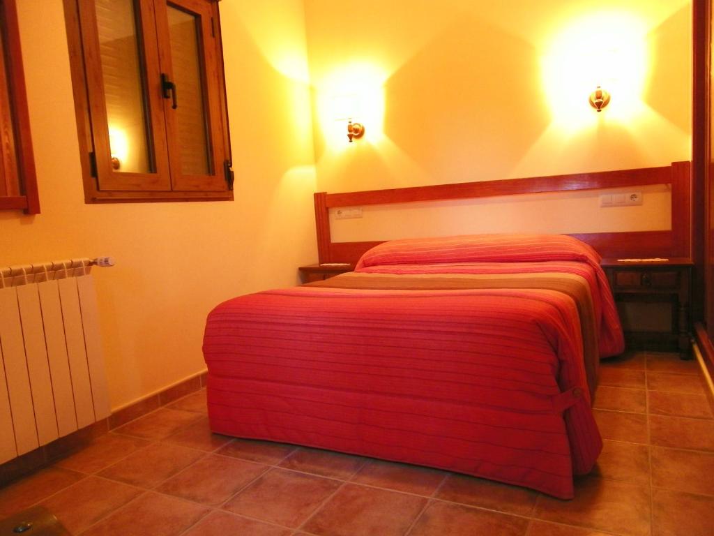 Casa Rural El Corralico في Ribadelago: غرفة نوم بسرير وبطانية حمراء