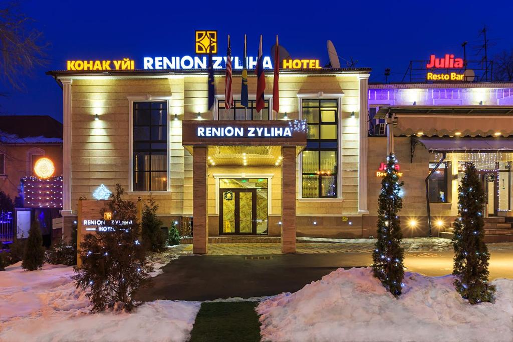 un hotel con un árbol de Navidad delante de él en Renion Zyliha Hotel en Almaty