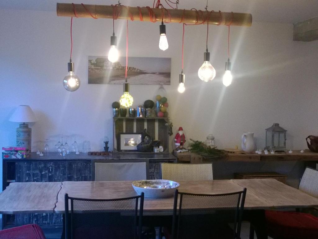 uma sala de jantar com uma mesa com cadeiras e luzes em Holiday home near the beach em Agon Coutainville