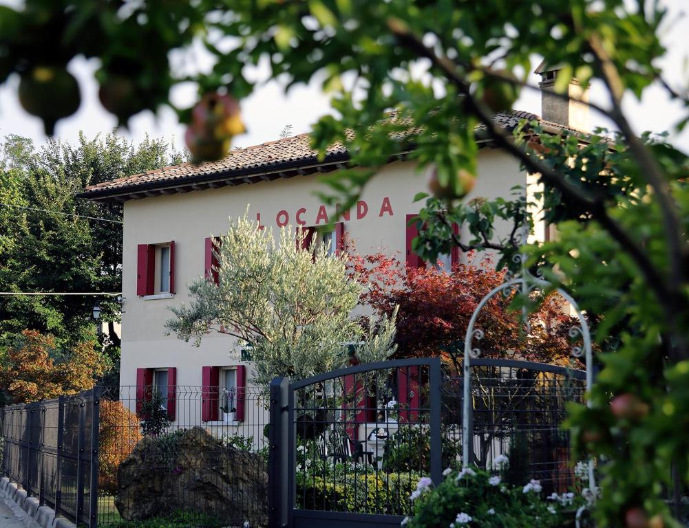 a white building with red windows and a fence at Locanda Bellavista in Cavaso del Tomba