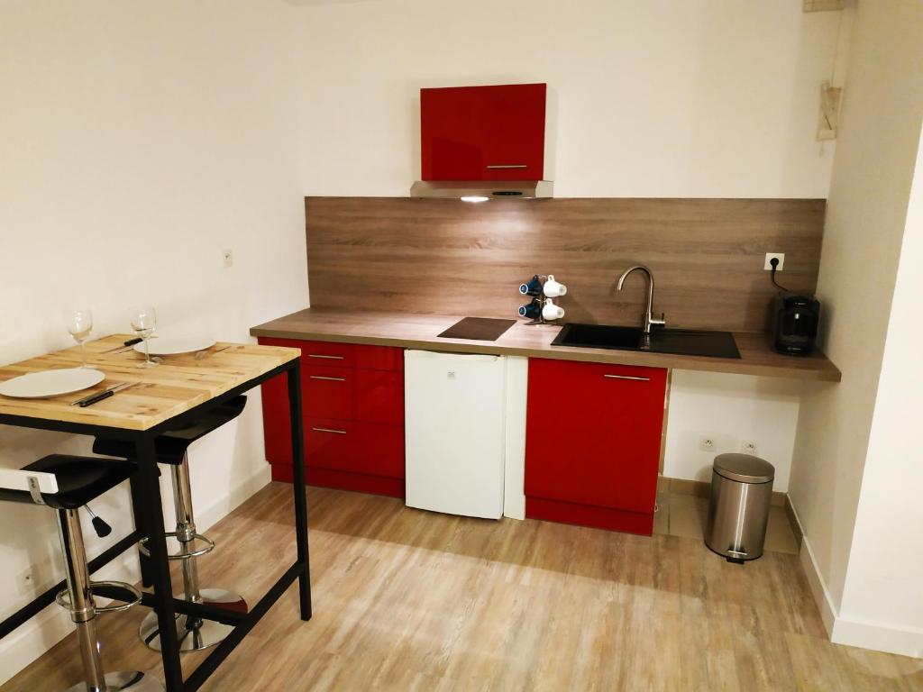 a small kitchen with red cabinets and a sink at Le New York Bisontin in Besançon