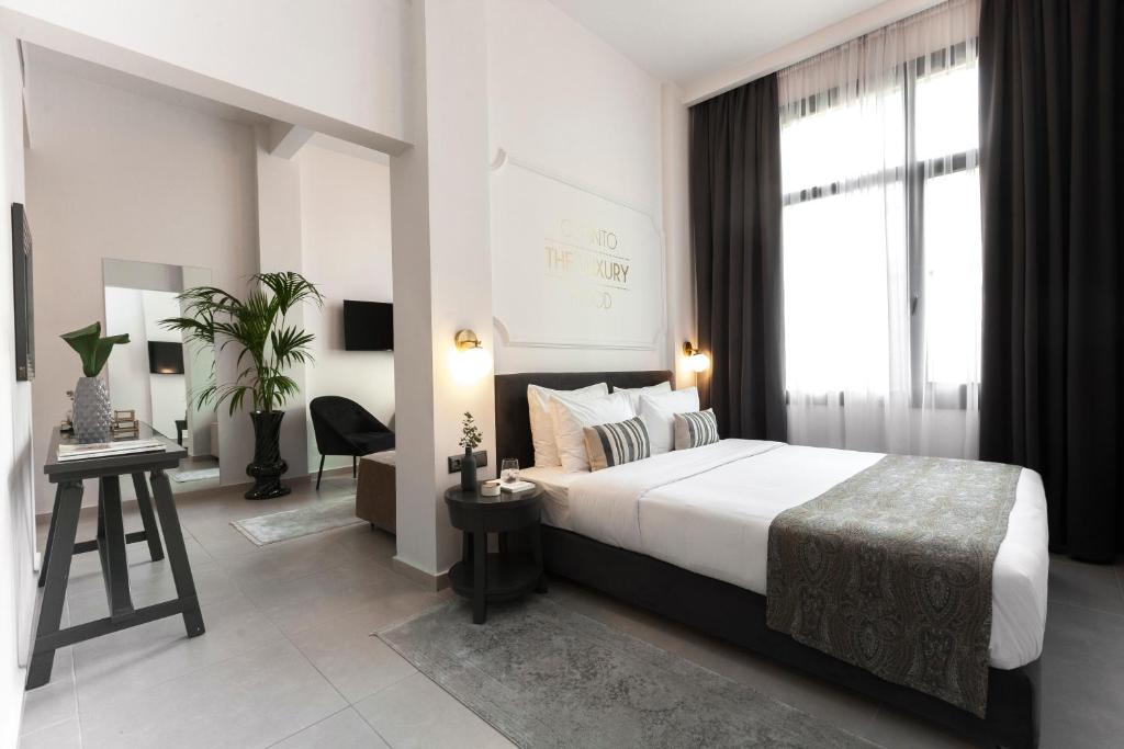 a bedroom with a bed and a desk and a window at The Mood Luxury Rooms in Thessaloniki