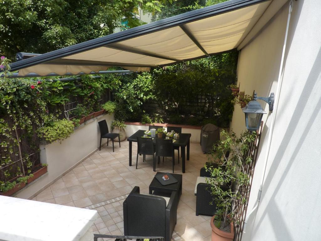 un patio con mesa y sillas bajo una sombrilla en Nice House Near Park and Sea en Génova