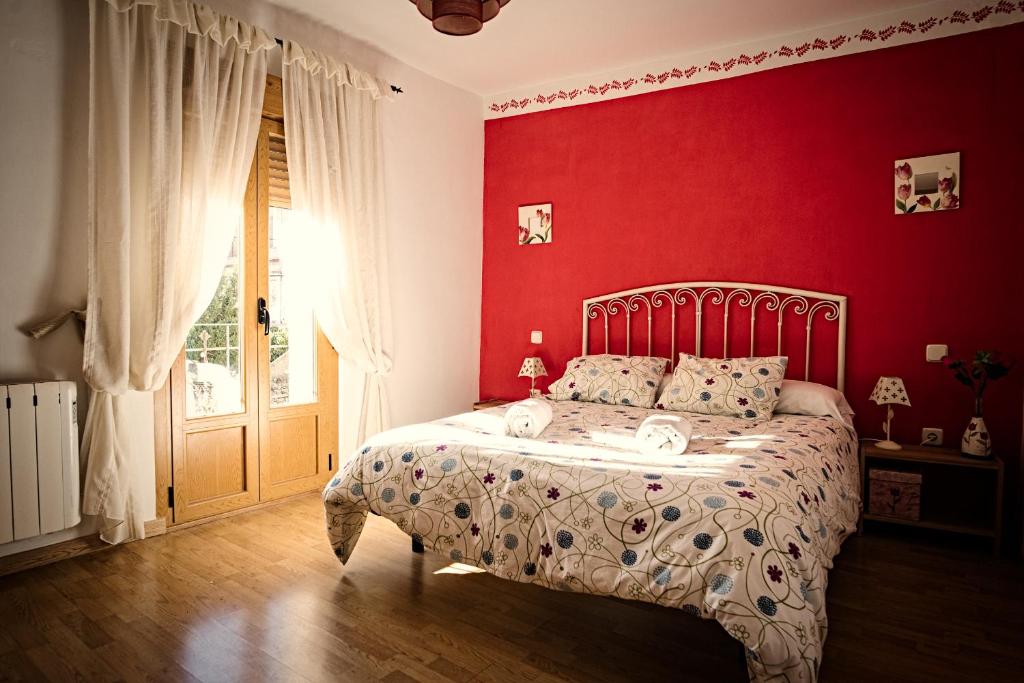 1 dormitorio rojo con 1 cama y pared roja en Casa Rural La Alegría de la Alcarria III en Torremocha del Campo