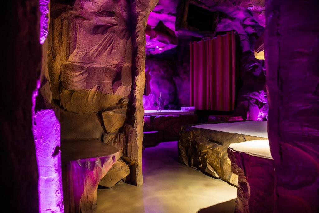 una camera con parete di roccia e luci viola di MagicSuite Guest House Roma Portuense a Roma