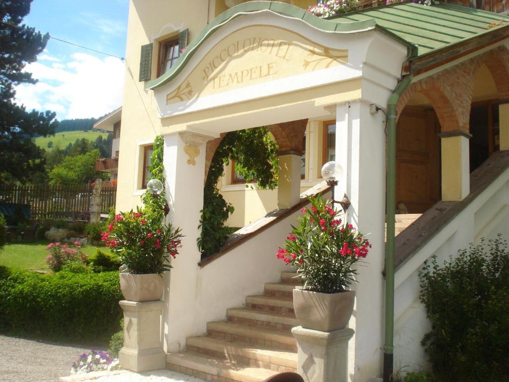 a house with stairs and flowers in pots at Piccolohotel Tempele Garni in San Candido