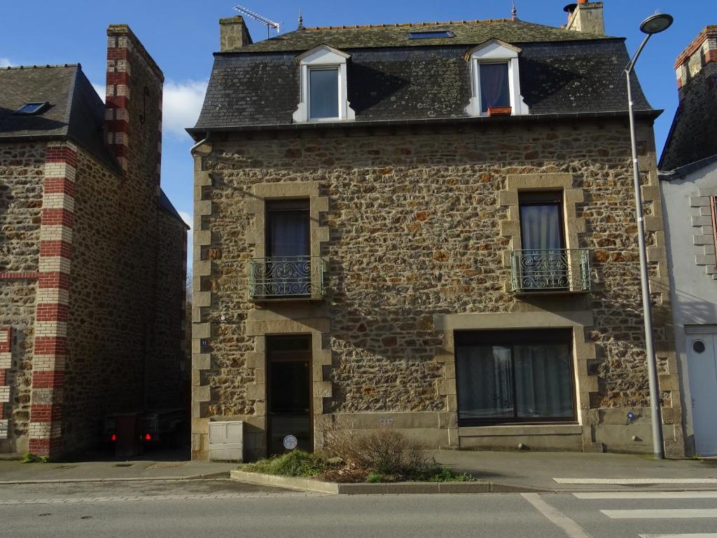 an old brick building with two windows and a balcony at Mahe in Plancoët