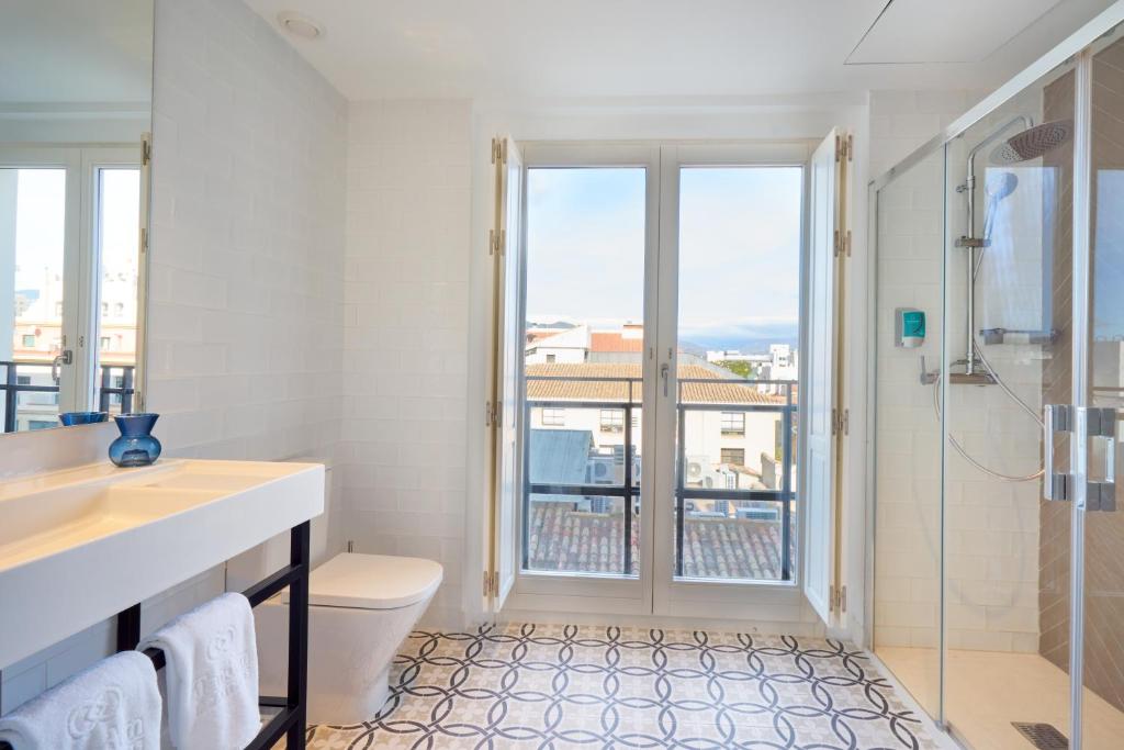 a bathroom with a toilet and a shower with a window at Tandem Soho Suites in Málaga
