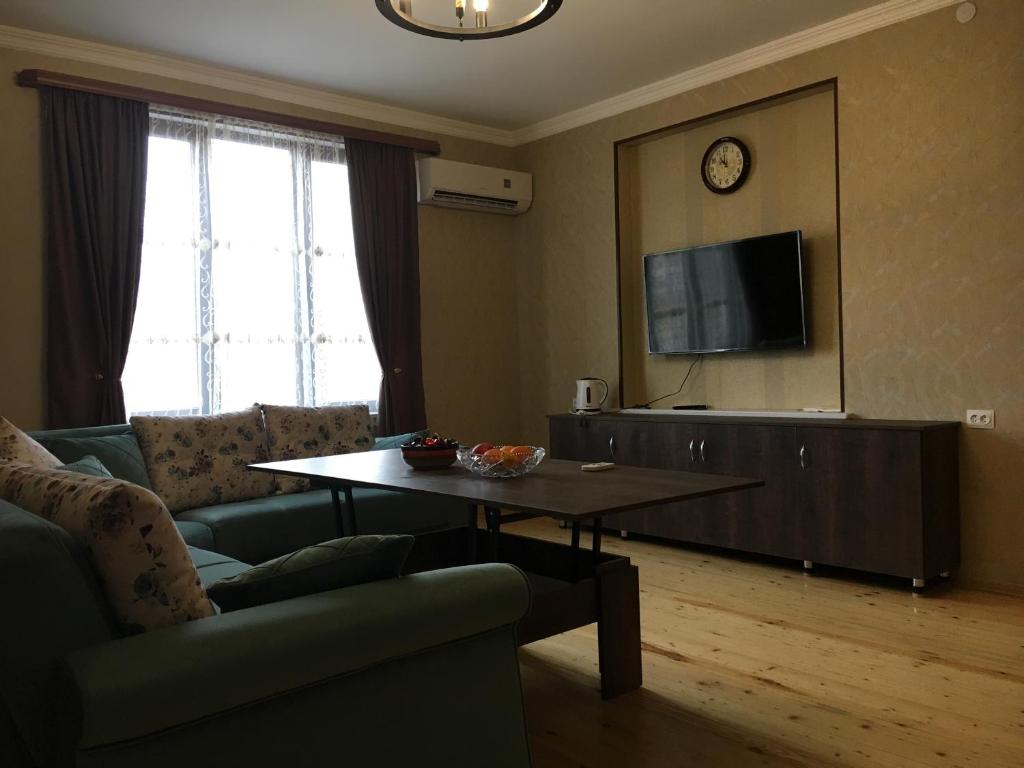 uma sala de estar com um sofá, uma mesa e uma televisão em Edward's Guesthouse em Lagodekhi