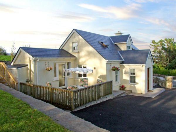 ein weißes Haus mit einem Zaun davor in der Unterkunft 1 Clancy Cottages in Kilkieran