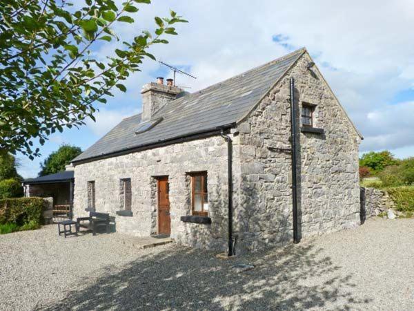 a stone house with a bench in front of it at Clooncorraun Cottage in Ballinrobe