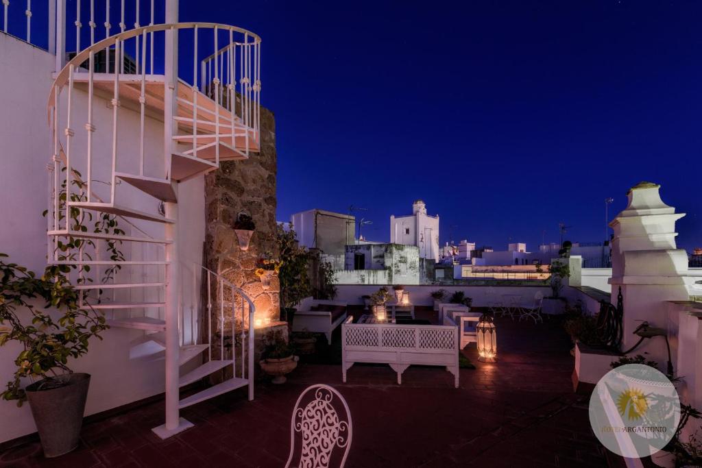 a balcony with a staircase and a table and chairs at Hotel Argantonio in Cádiz