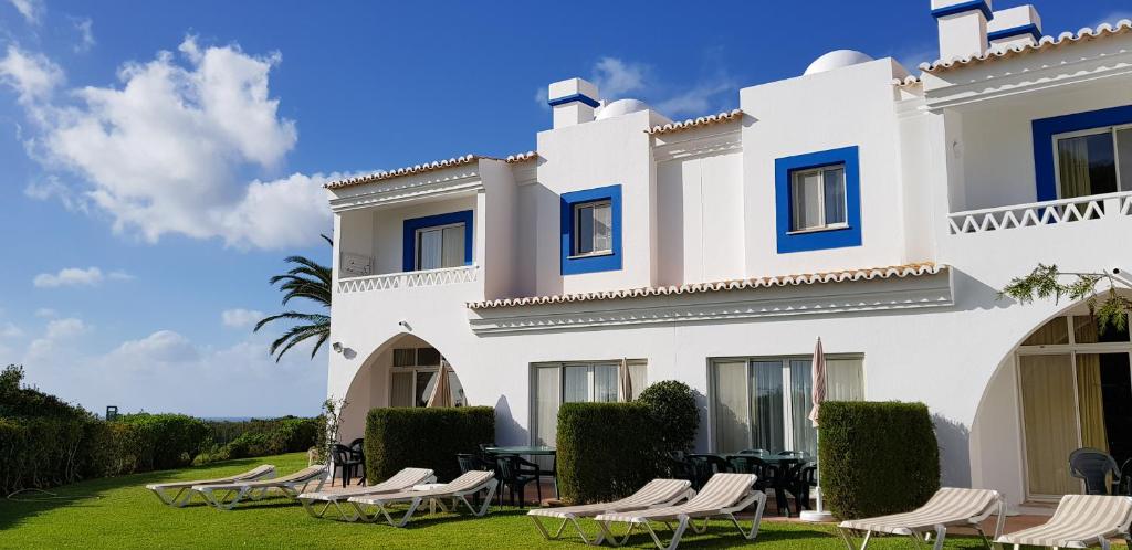 a white building with chairs and tables in front of it at Pestana Palm Gardens in Carvoeiro