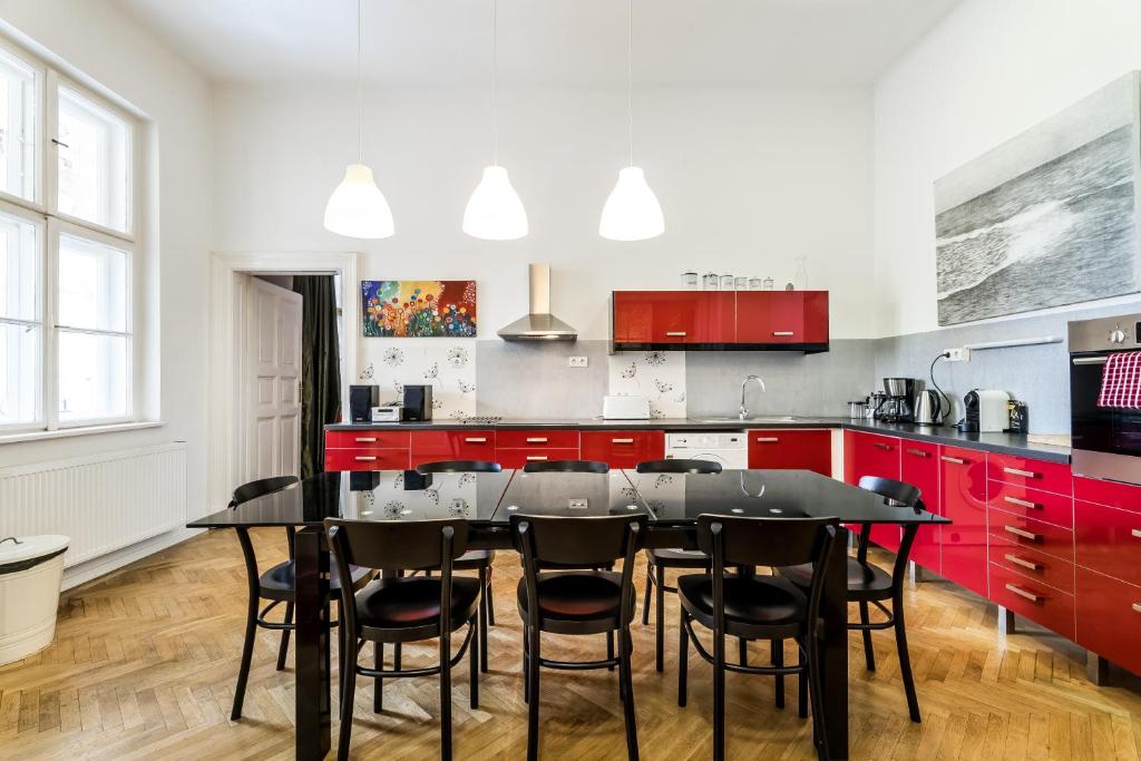 cocina con armarios rojos, mesa negra y sillas en BERTA - 4 Bedrooms, 3 Baths en Budapest