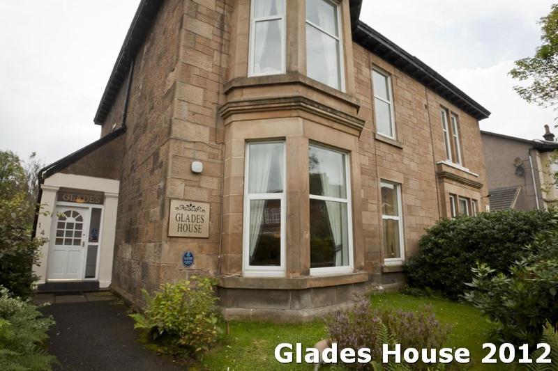 une grande maison en briques avec une porte blanche dans l'établissement Glades House, à Glasgow