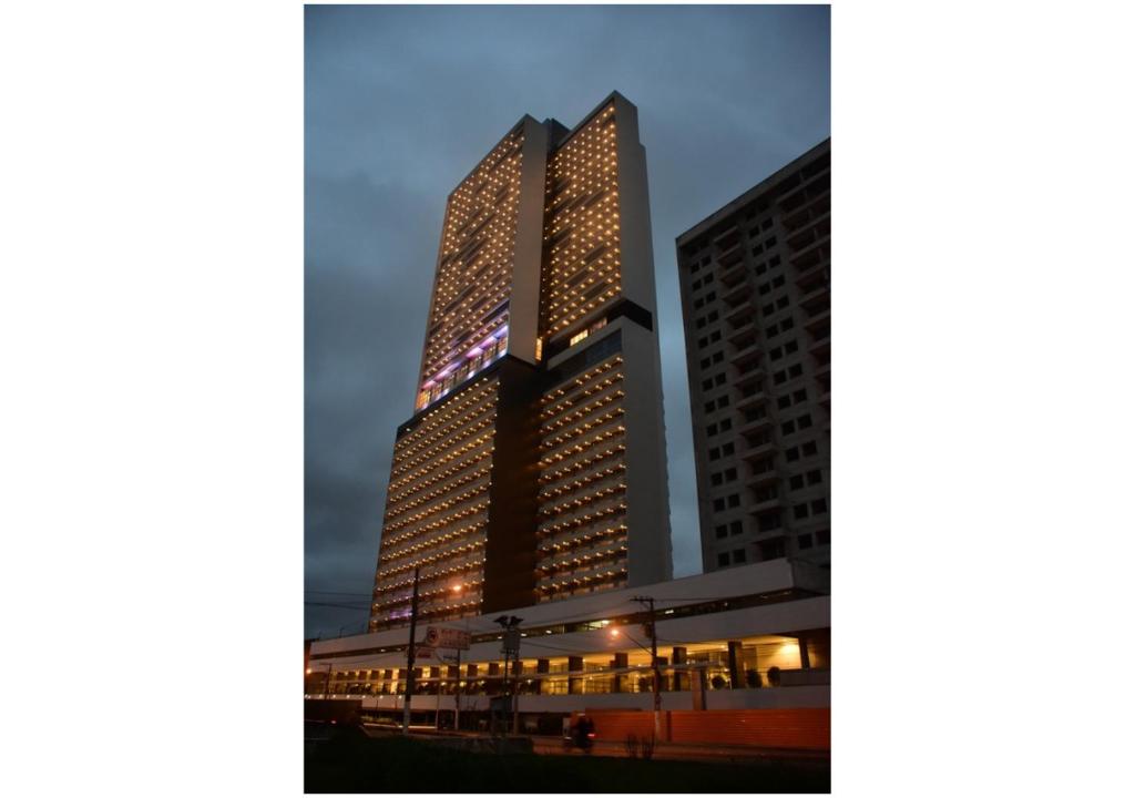 a tall building with lights on it at night at Flat Aconchego, próximo ao centro de Osasco, ar condicionado, academia, piscina, wifi e varanda in Osasco