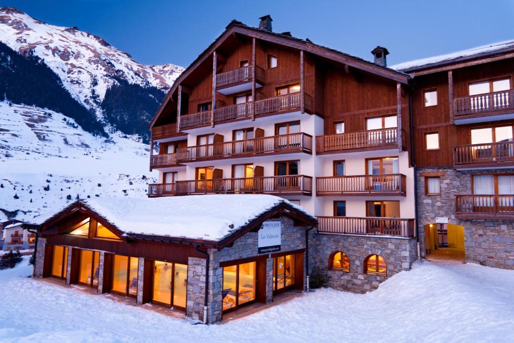 een groot gebouw in de sneeuw voor een berg bij Lagrange Vacances Les Valmonts de Val Cenis in Lanslebourg-Mont-Cenis