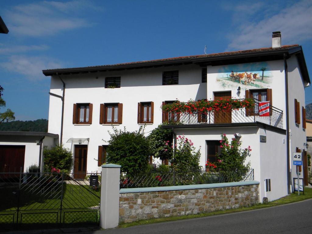 a white house with flowers on the balcony at Agriturismo Alle Ruote in Meduno