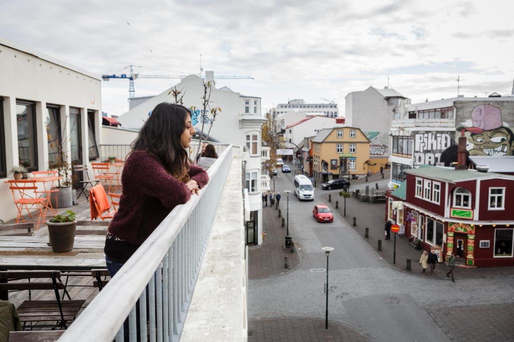 a woman standing on a balcony looking out at a city at Loft - HI Hostel in Reykjavík