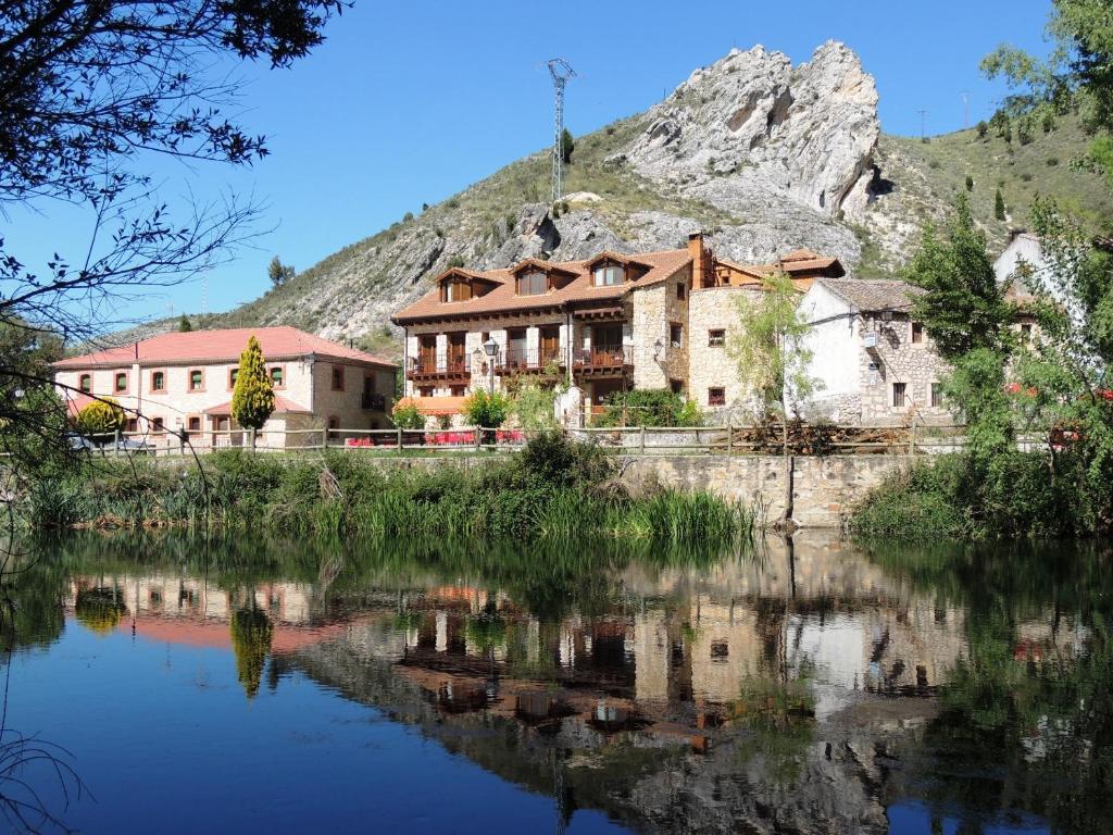 uma casa em frente a uma montanha ao lado de um lago em El Rincón de las Hoces del Duratón em Burgomillodo