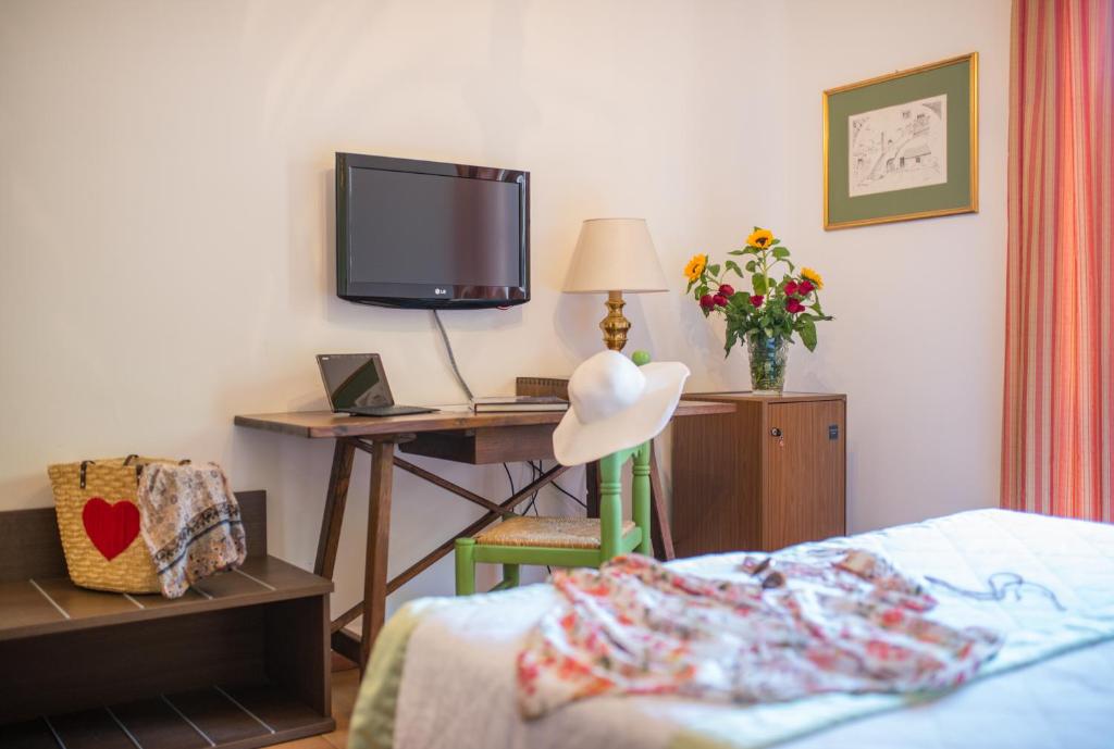 a bedroom with a bed and a desk with a tv at Hotel Villa Sirina in Taormina