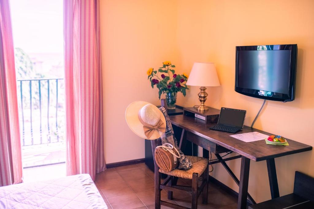 a room with a desk with a laptop and a television at Hotel Villa Sirina in Taormina