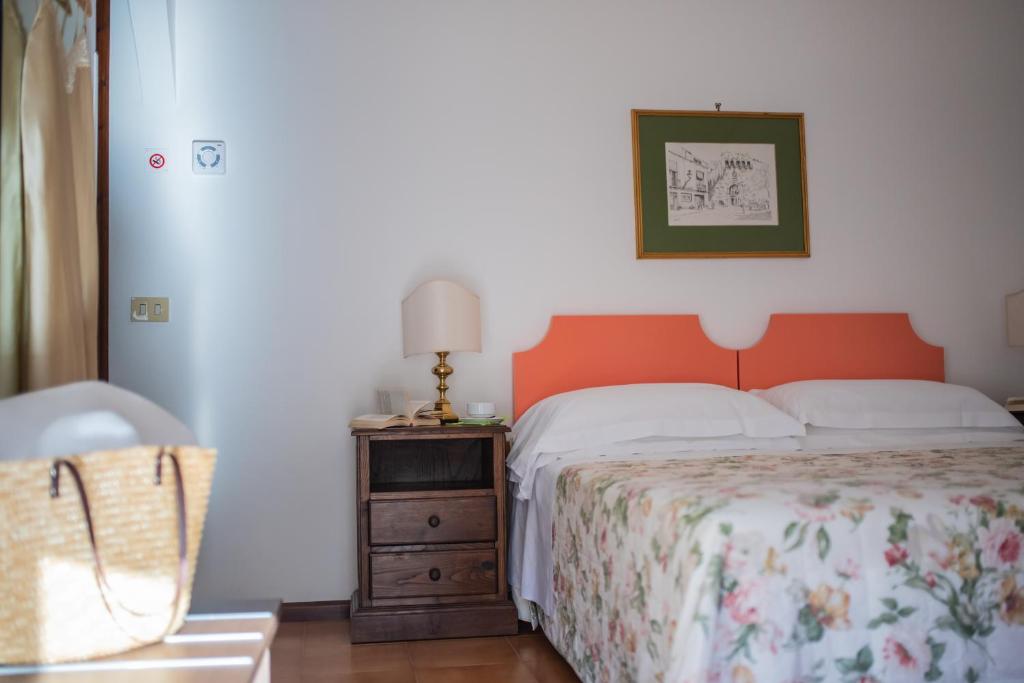a bedroom with a bed with an orange headboard at Hotel Villa Sirina in Taormina