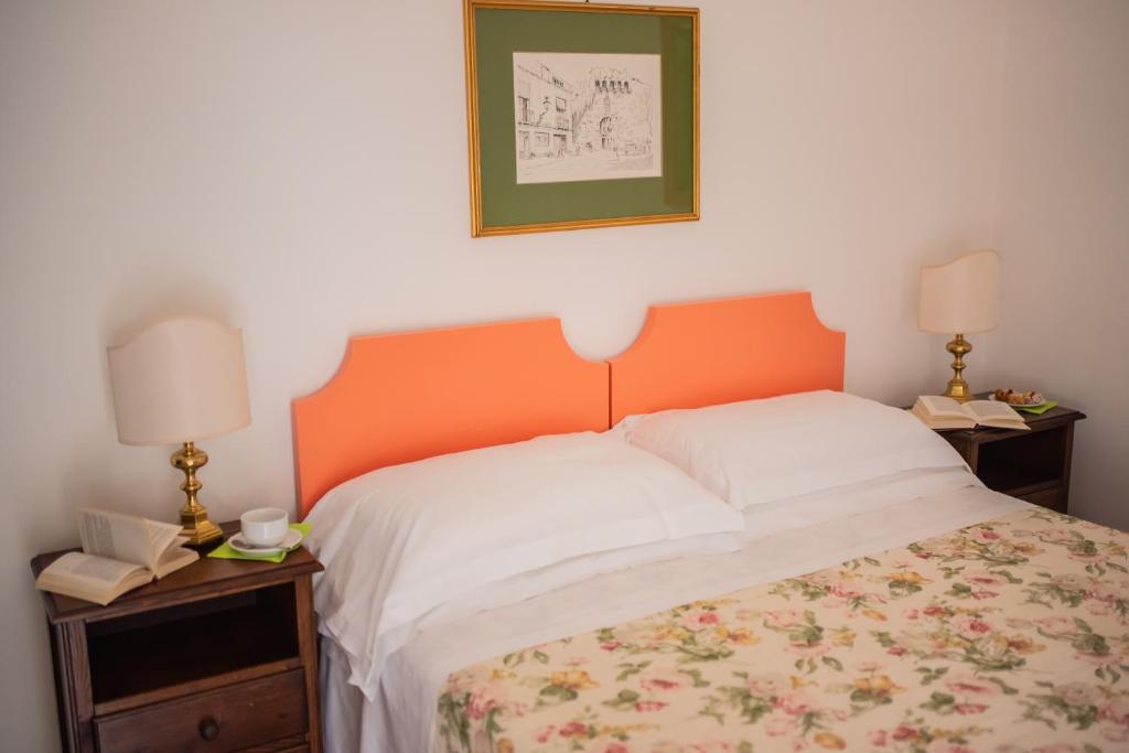 a bedroom with a bed with an orange headboard and two lamps at Hotel Villa Sirina in Taormina