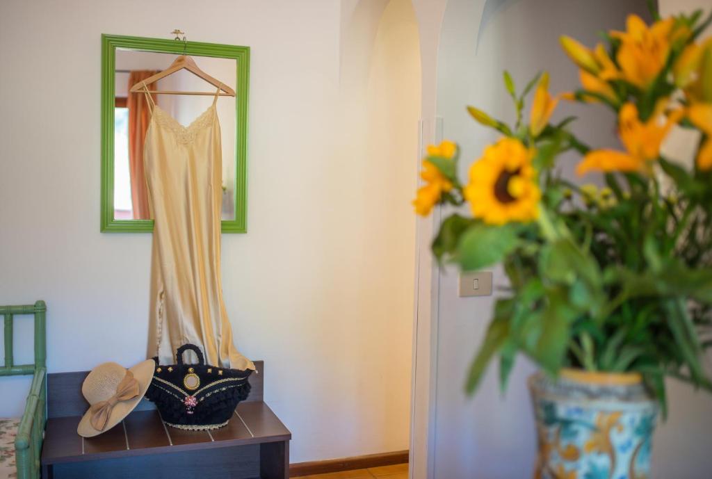 a dressing table with a dress and a vase of flowers at Hotel Villa Sirina in Taormina