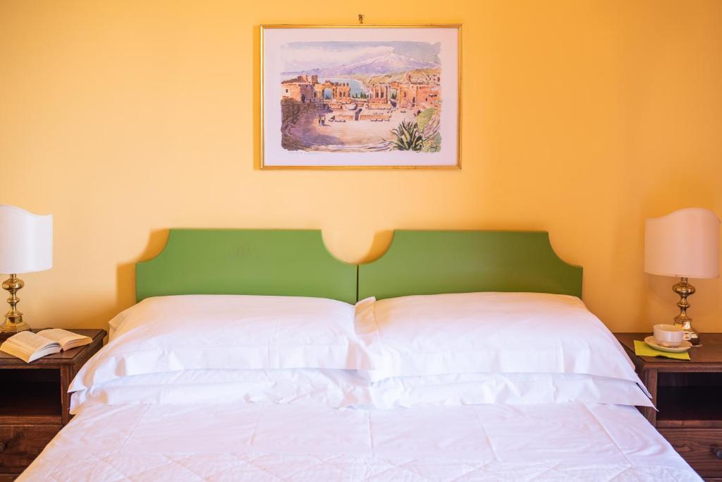a bedroom with a white bed with a green headboard at Hotel Villa Sirina in Taormina