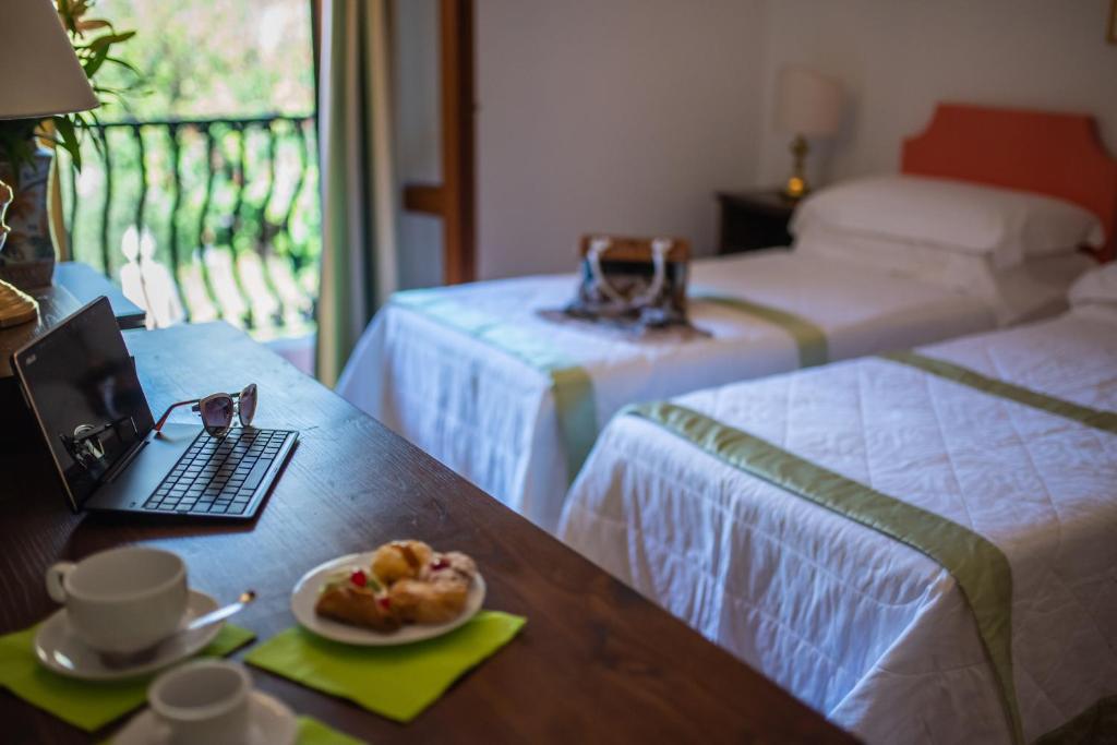 a room with two beds and a table with a plate of food at Hotel Villa Sirina in Taormina
