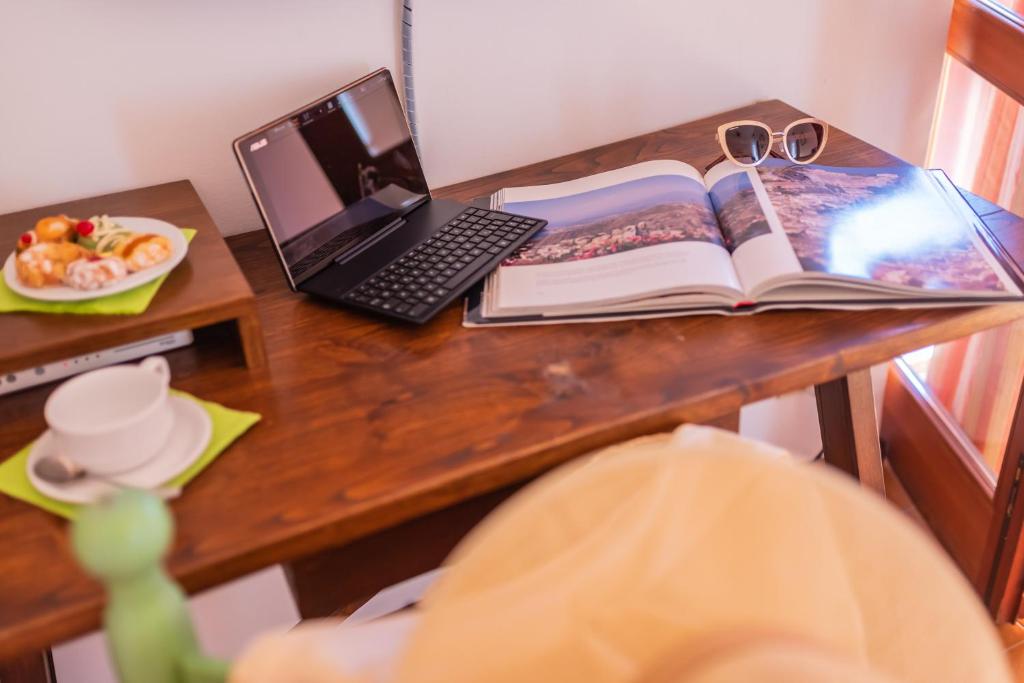 a desk with a laptop and an open book and a book at Hotel Villa Sirina in Taormina