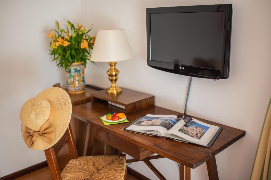 a desk with a television and a book and a chair at Hotel Villa Sirina in Taormina