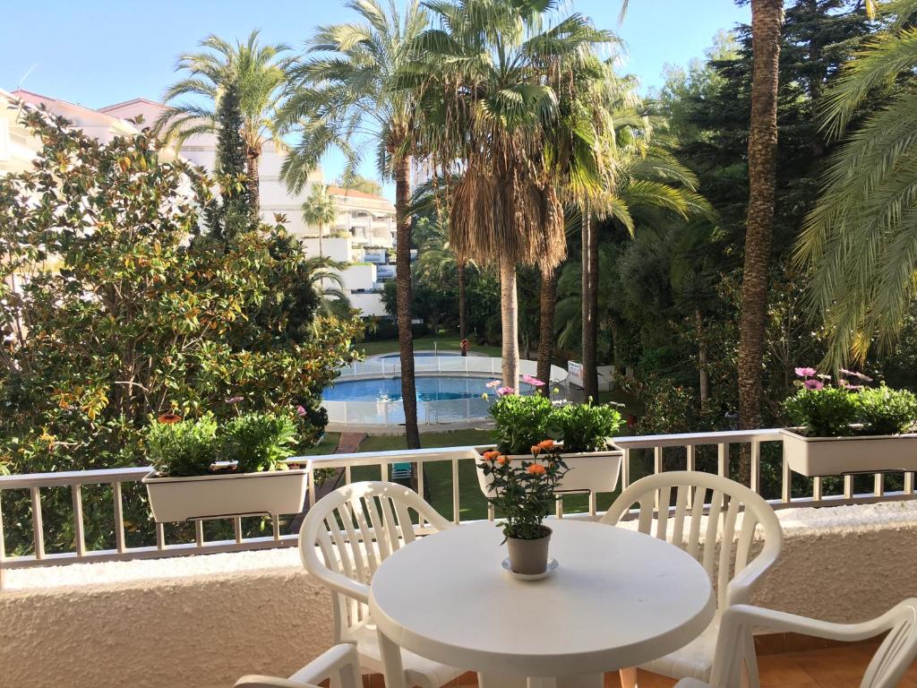 a white table and chairs on a balcony with palm trees at Quiet place to stay in Marbella