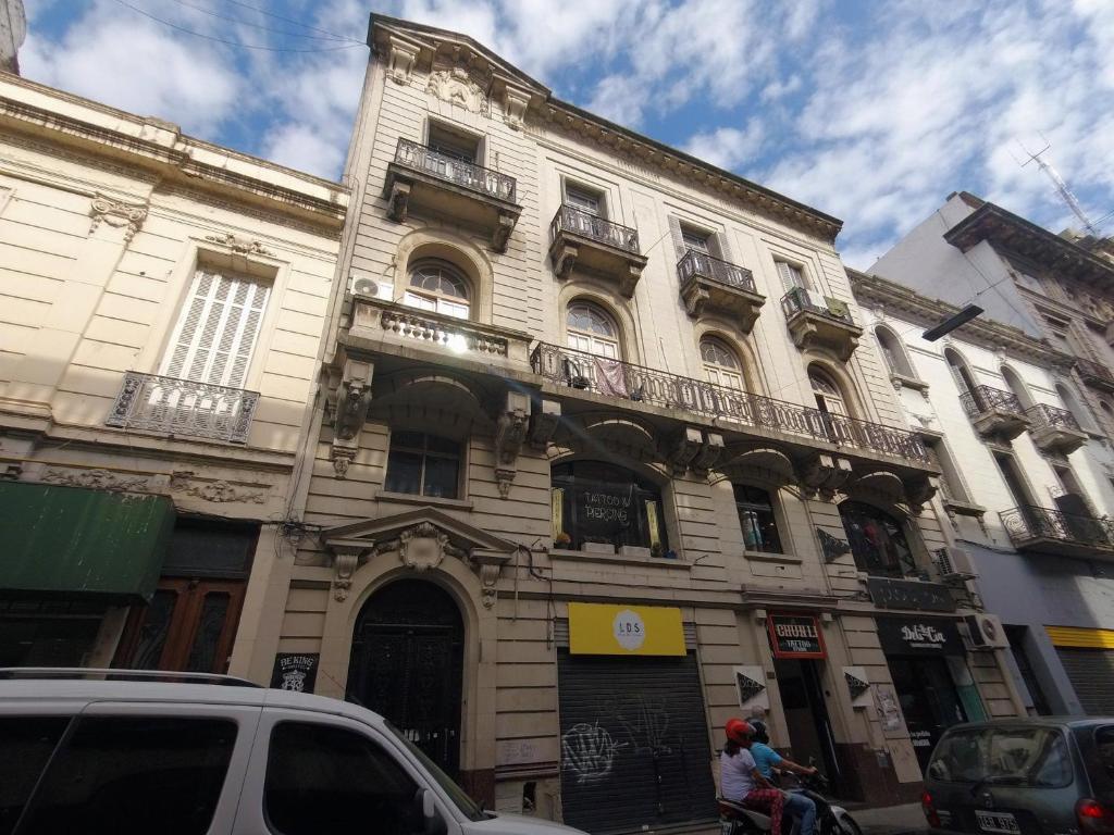 een gebouw in een straat waar auto's voor geparkeerd staan bij Be King Hostel in Rosario