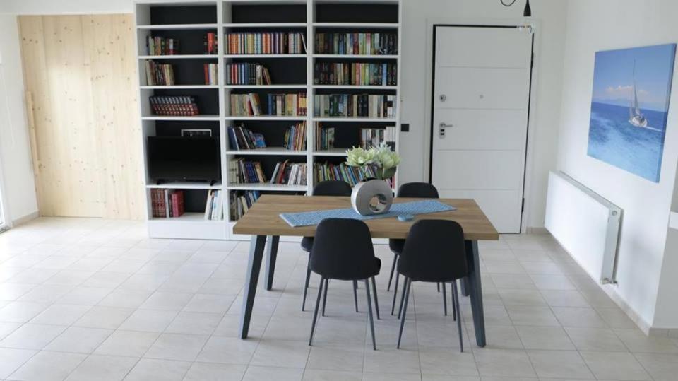 a dining room with a table and chairs and bookshelves at AZZURO in Kavála