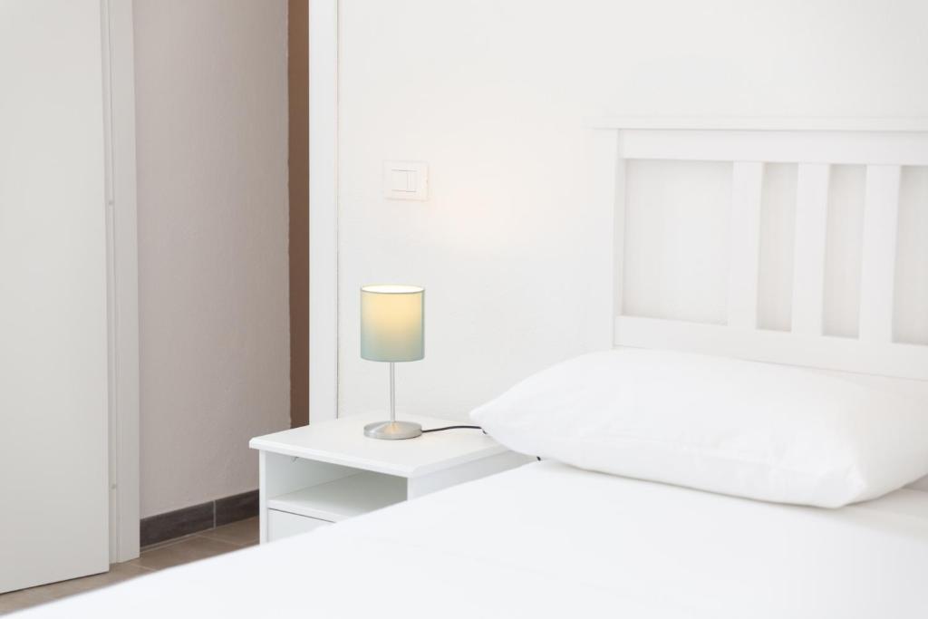 Dormitorio blanco con cama y mesita de noche con lámpara en Casa Leonardo, en Isquia
