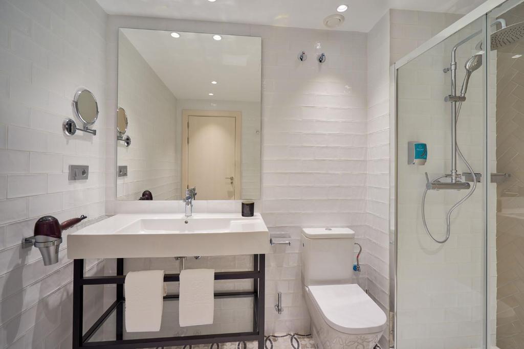 a bathroom with a sink and a toilet and a shower at Tandem Soho Suites in Málaga