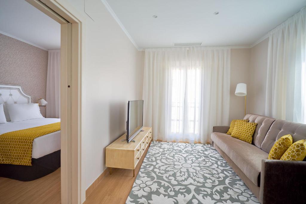a hotel room with a bed and a couch at Tandem Soho Suites in Málaga